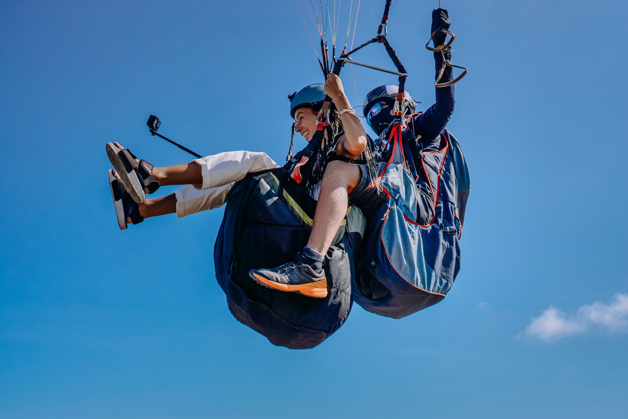 woman-with-instructor-flying-on-parachute-against-sky